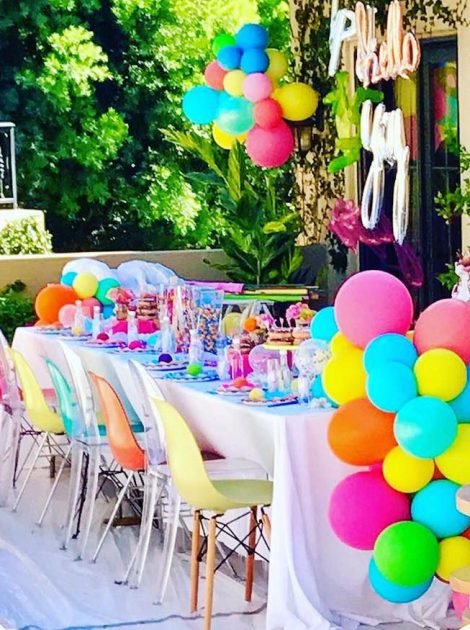 Vibrant outdoor party table decorated with colorful balloons, sweets, and cheerful accents