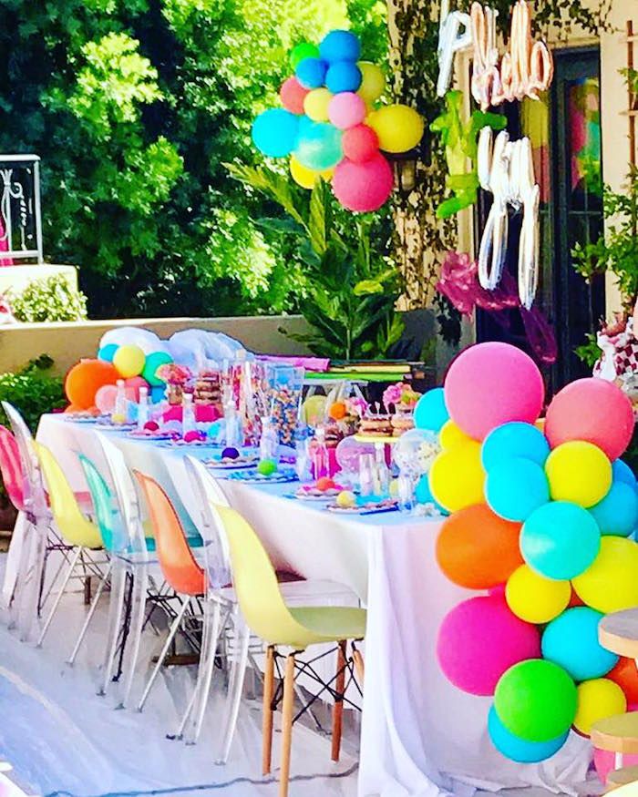 Vibrant outdoor party table decorated with colorful balloons, sweets, and cheerful accents