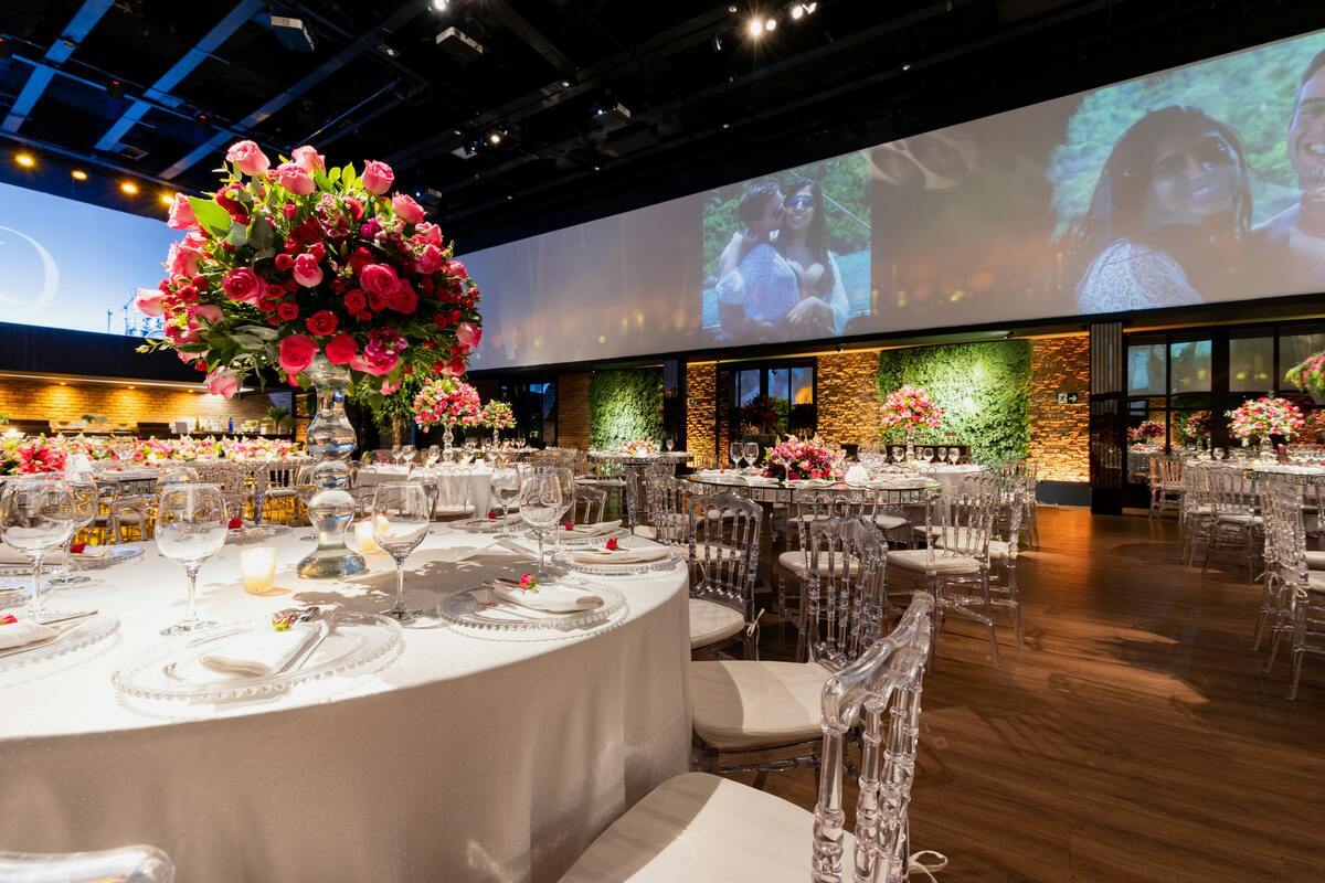 Elegant event space with round tables, floral centerpieces, crystal glassware, and soft lighting